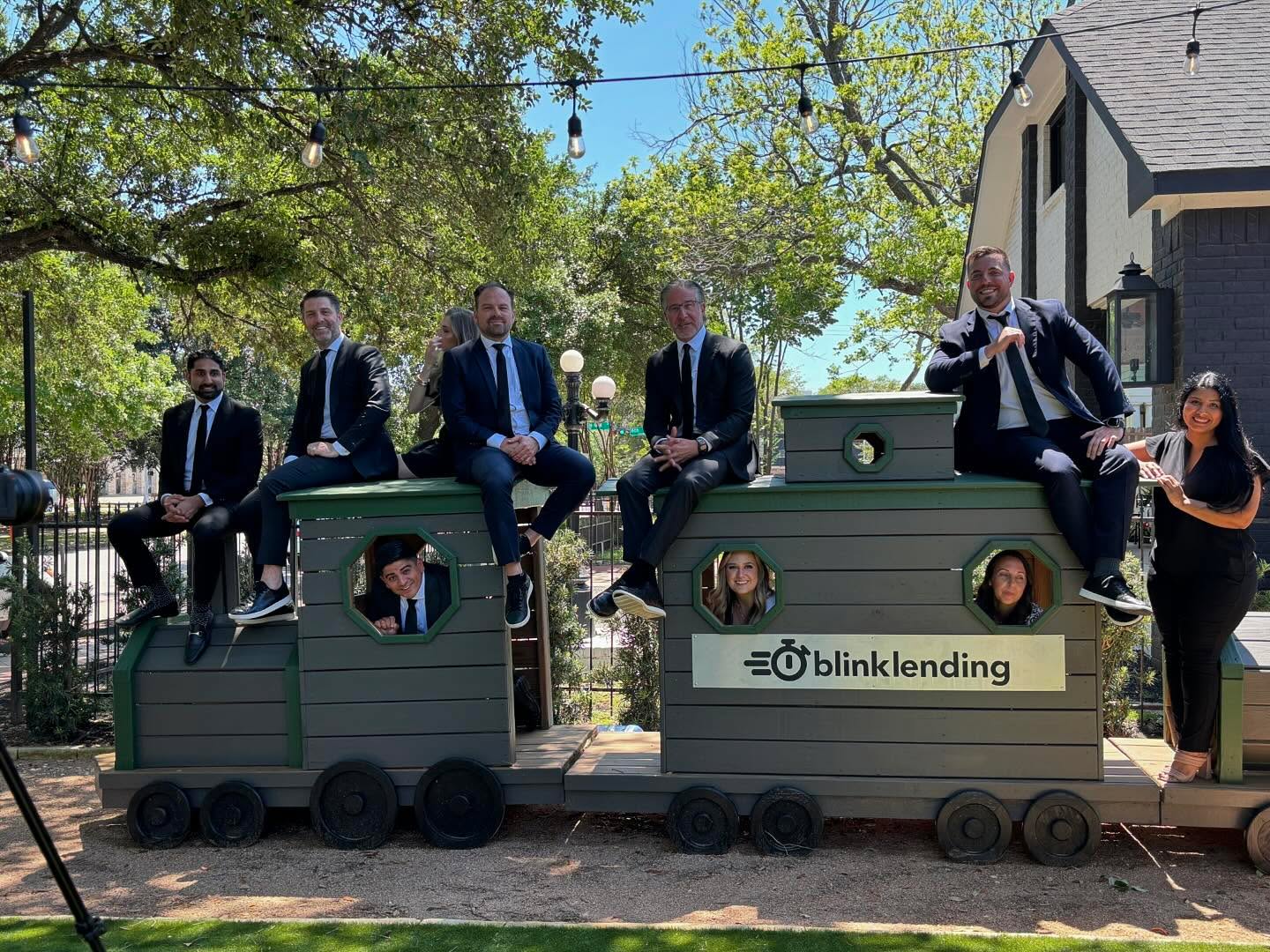 Blink Lending team photo on Blink Lending branded train in front of their office. src=